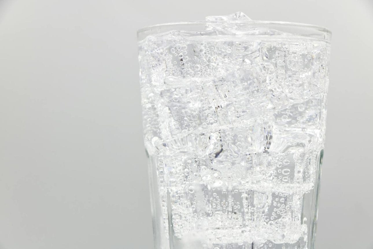 Close-up of a glass filled with sparkling water and ice cubes, ideal for refreshing summer drinks.
